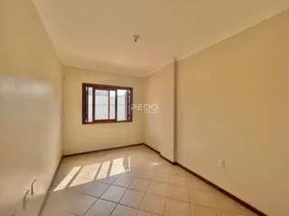 Corredor interno com piso de cerâmica e janela de madeira.