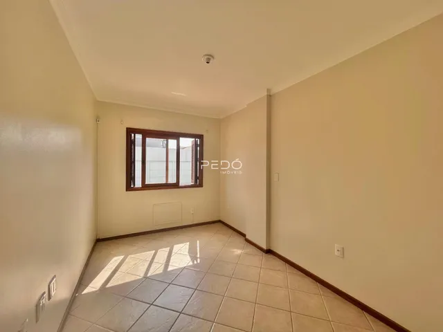 Corredor interno com piso de cerâmica e janela de madeira.