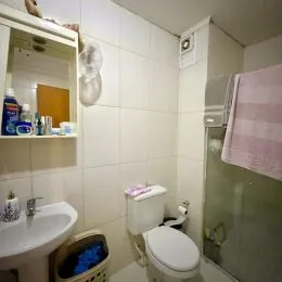 Foto interna de um banheiro com revestimento de azulejos brancos.