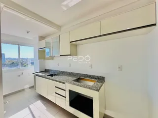 Vista da cozinha moderna com armários brancos e bancada de granito.
