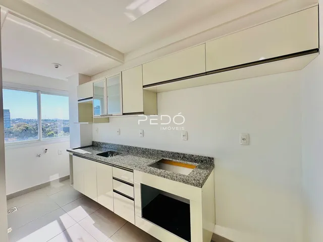 Vista da cozinha moderna com armários brancos e bancada de granito.