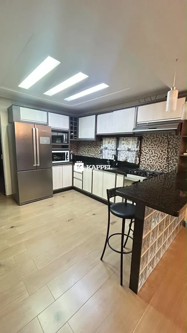 Cozinha moderna com armários brancos e bancada escura em um ambiente bem iluminado.