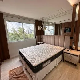 Foto de um quarto com cama grande e piso de madeira clara.