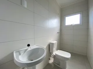 Foto interna de um banheiro com pia e vaso sanitário brancos.