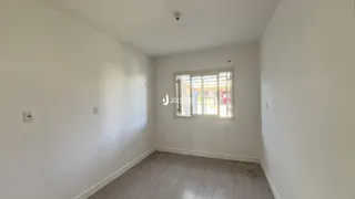 Foto de um cômodo interno com paredes brancas e piso de madeira clara.