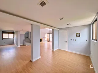 Sala de estar ampla com piso de madeira clara e paredes cinzas.