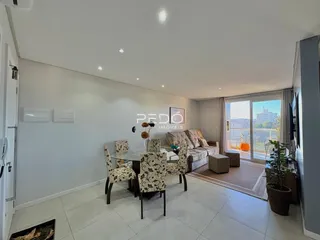 Sala de estar com mesa de jantar e vista para o exterior.