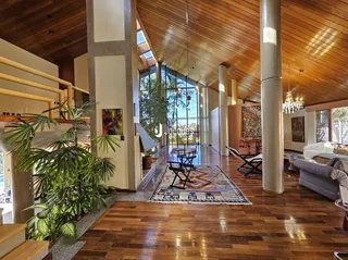 Imagem de uma sala de estar com piso de madeira e grandes janelas.