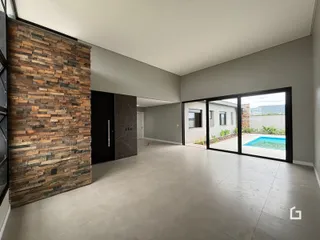 Interior de uma sala de estar com parede de pedra e portas de vidro que dão acesso a uma área externa com piscina.