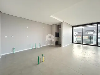 Ambiente interno de uma sala ampla com piso de concreto e paredes brancas.