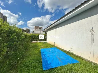 Fachada de uma casa com gramado e lona azul no quintal.