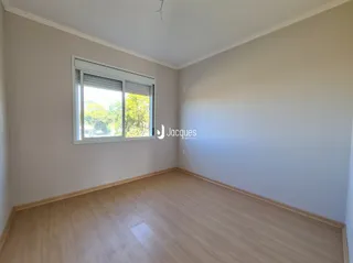 Sala de estar com piso de madeira clara e janela.