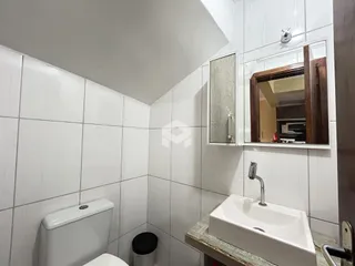 Banheiro com revestimento cerâmico branco e pia.