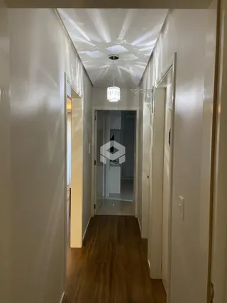 Corredor interno de uma residência com piso de madeira.