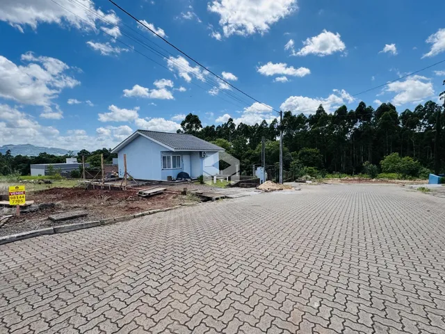 Vista externa de uma casa em construção com área pavimentada no quintal.