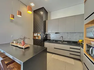 Cozinha moderna com armários cinzas e parede de tijolos escuros.