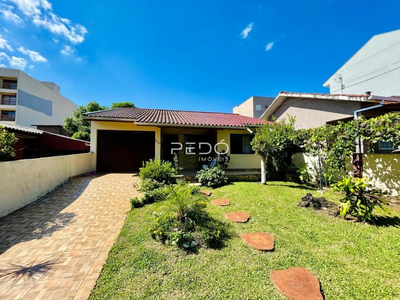 Vista externa de uma residência com jardim e entrada de garagem em Lajeado.
