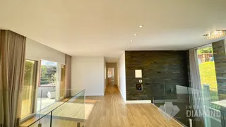 Sala de estar com piso de madeira clara e parede de destaque rústica.