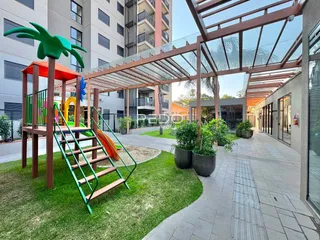 Área externa com gramado e playground em um condomínio residencial.