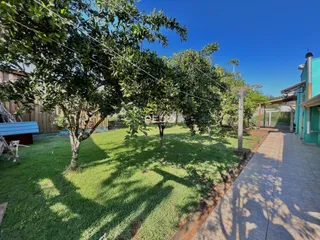 Vista externa de um jardim com gramado e árvores sob luz solar.
