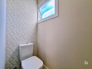 Vista parcial de um banheiro com azulejos brancos e uma janela.