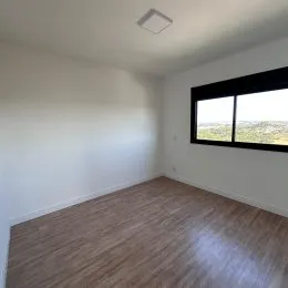 Foto de um cômodo interno com piso de madeira e janela.