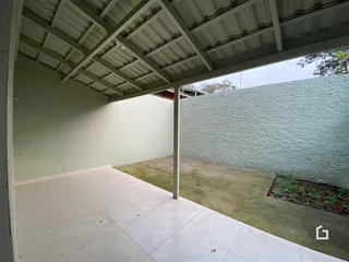 Vista de uma área externa com piso de cerâmica e gramado.