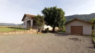 Fachada de uma casa em Lajeado, Brasil, com vegetação e terreno gramado.
