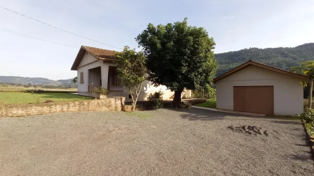 Fachada de uma casa em Lajeado, Brasil, com vegetação e terreno gramado.