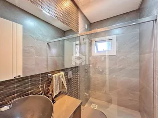 Foto de um banheiro com revestimento de azulejos e box de vidro.