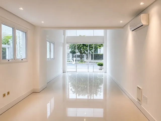 Hall de entrada com piso claro e grandes janelas que dão vista para o exterior.