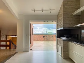 Sala de estar com piso claro e vista para o exterior através de portas de vidro.