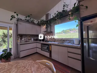 Cozinha moderna com armários claros e vista para o exterior.
