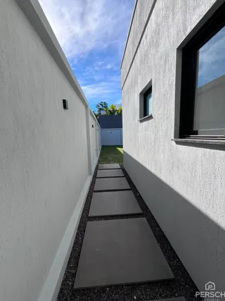 Uma foto de um caminho externo estreito entre duas paredes brancas.