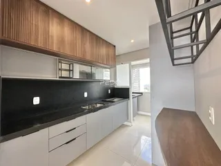 Vista da cozinha moderna com armários de madeira e bancadas escuras.