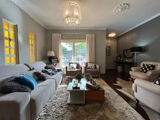 Sala de estar com sofás claros e piso de madeira no interior da residência.