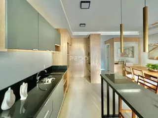 Vista da cozinha moderna com armários e bancadas escuras em um imóvel no Brasil.