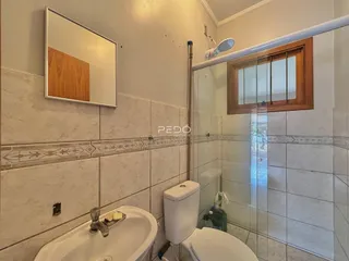 Foto interna de um banheiro com revestimento cerâmico e box de vidro.