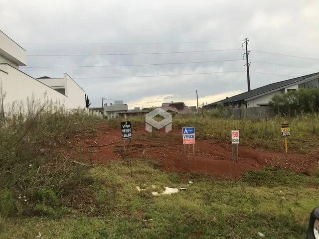 Paisagem de terreno com vegetação e construções ao fundo.