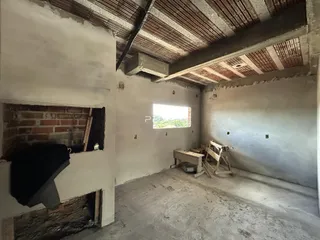 Imagem de um cômodo interno em construção com paredes de alvenaria expostas.