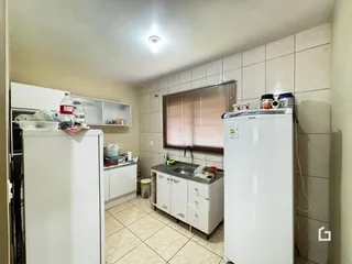 Foto da cozinha com armários brancos e piso de cerâmica.