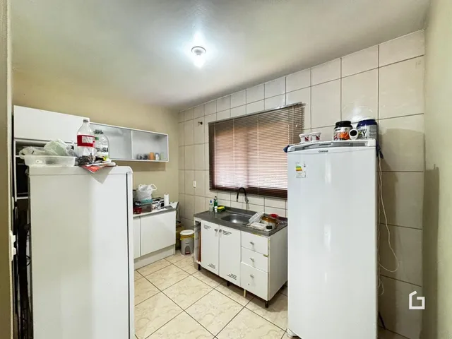 Foto da cozinha com armários brancos e piso de cerâmica.
