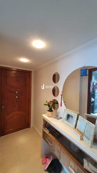 Hall de entrada com porta de madeira e prateleira branca.