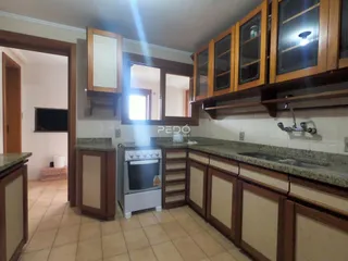 Vista da cozinha com armários de madeira e bancadas de granito.