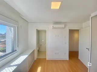 Hall de entrada com piso de madeira e janela.