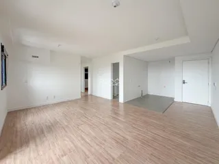 Ambiente interno de uma sala ampla com piso de madeira clara.