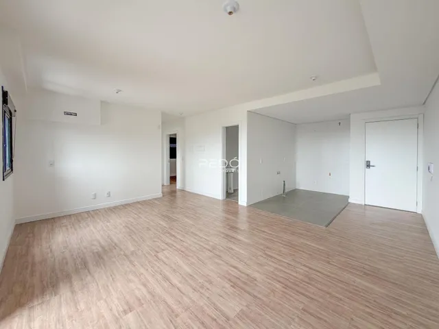Ambiente interno de uma sala ampla com piso de madeira clara.