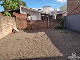 Área externa com piso de cascalho adjacente a um muro de tijolos.