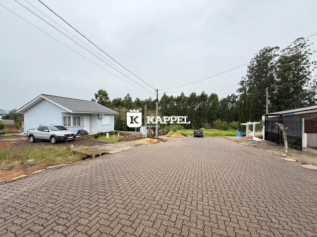 Foto externa da fachada de uma casa em uma área com vegetação ao fundo.