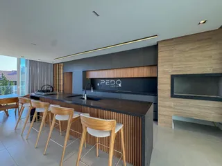 Vista de uma cozinha moderna com ilha e área de jantar em um imóvel no Brasil.